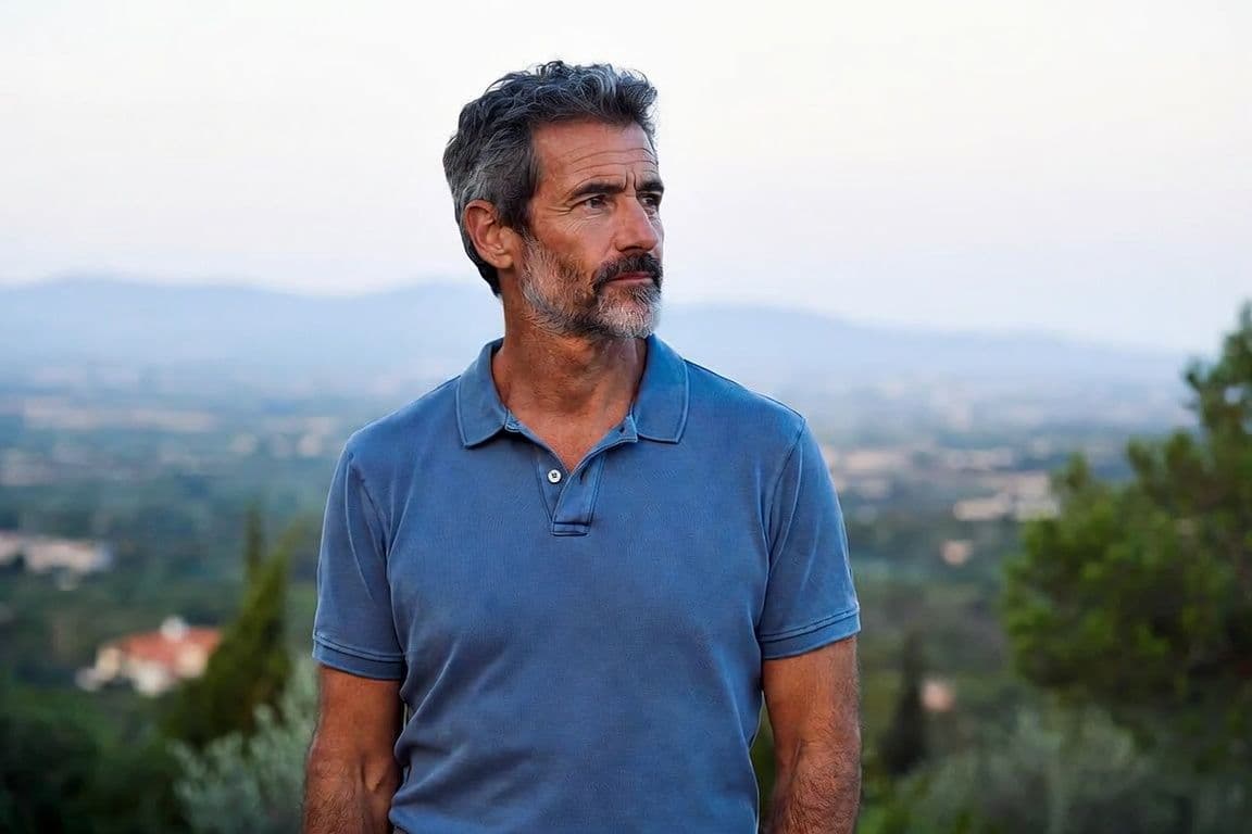 Homme de 55 ans s'étirant sur une terrasse méditerranéenne évoquant la rééducation périnéale et la fuite urinaire homme Homme de 55 ans s'étirant sur une terrasse méditerranéenne évoquant la rééducation périnéale et la fuite urinaire homme