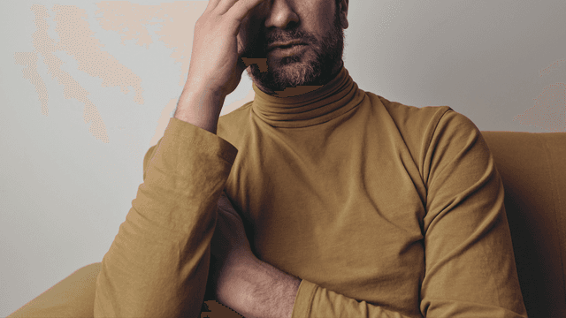 Homme assis sur un lit, l'air pensif, illustrant l'anxiété de performance sexuelle Homme assis sur un lit, l'air pensif, illustrant l'anxiété de performance sexuelle